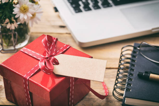 istock Red gift box with empty blank tag, blur office desk background 1050445832