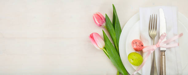 istock Easter table setting with pink tulips on white wooden background. Top view, copy space, banner 1050445910