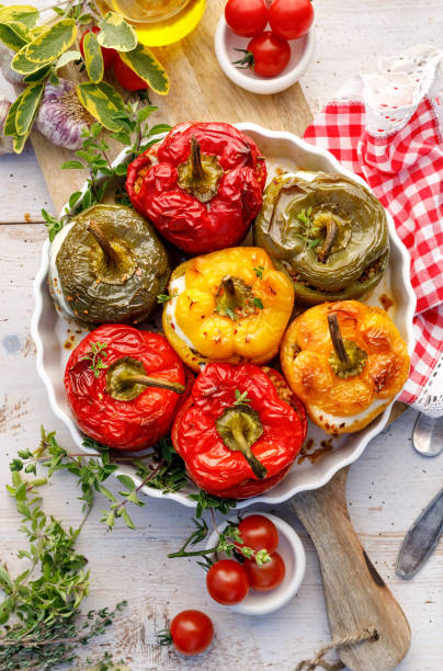 farcis de poivrons cuits au four. champignons, riz, fromage et herbes poivrons farcis dans un plat allant au four sur une table en bois blanc. - greek cuisine greek culture food table photos et images de collection