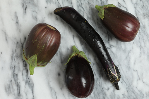 A close up horizontal photograph of several ripe homegrown eggplants, the long one is a Japanese variety and the rest are Black Beauties.