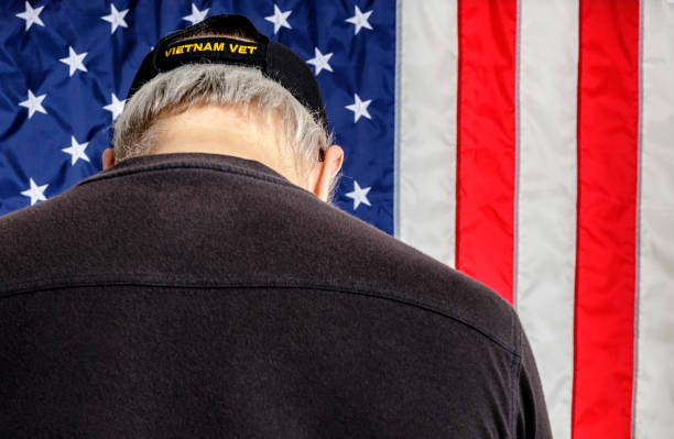 moment der stille u.s. navy vietnam veteran verbeugung kopf mit amerikanischer flagge hintergrund - baseball cap old red caucasian stock-fotos und bilder