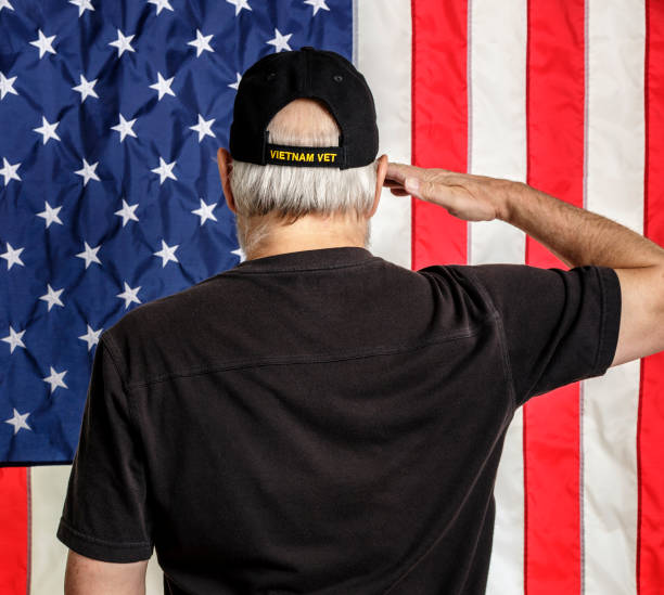 älteren erwachsenen mannes u.s. navy vietnam-veteran salutieren amerikanische flagge - baseball cap old red caucasian stock-fotos und bilder