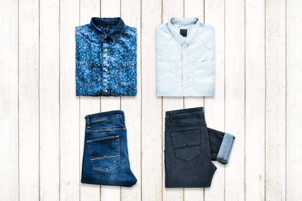 Men's two folded shirts and two folded jeans arranged as square flat lay on white wooden background