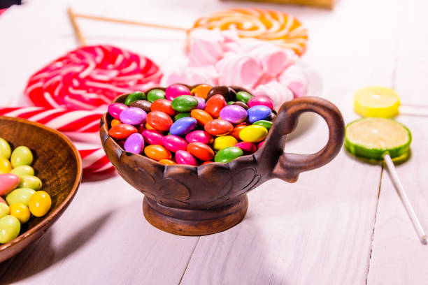 istock Ceramic bowl with colored candies, lollipops and marshmallows on a wooden table 1050485132