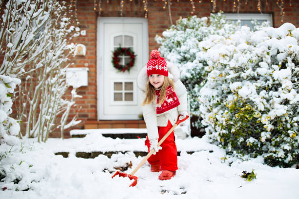 ребенок лопатой зимний снег. дети расчищали дорогу. - wreath christmas door snow стоковые фото и изображения