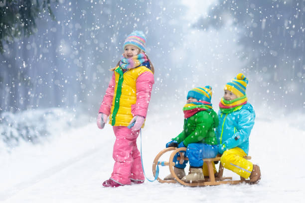 i bambini giocano nella neve. giro in slitta invernale per bambini - 16607 foto e immagini stock