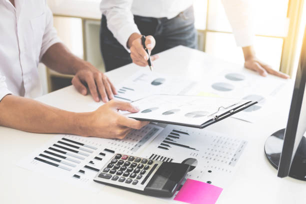 istock Midsection Of Businessmen Discussing Over Graph While Working On Table At Office 1050533112