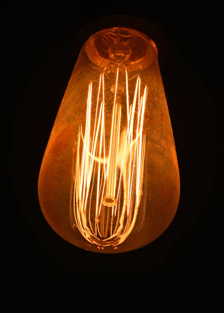 istock Close-Up Of Illuminated Light Bulb Against Black Background 1050551074