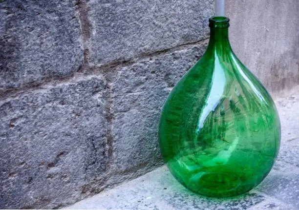 Vintage large green glass wine bottle on the sidewalk.