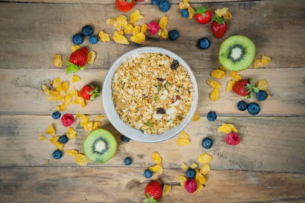Bowl of cereal with fresh fruit and cornflakes on the wooden table