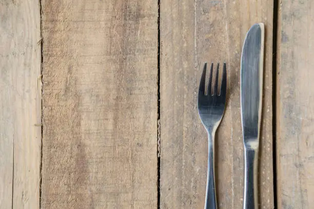Close up of a silver knife and fork on the wooden table