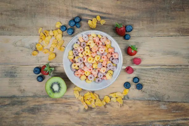 Top view of tasty cereal with fresh fruit and cornflakes on the wooden table