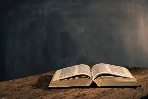 Bible on a old oak wooden table. Beautiful dark background. Religion concept