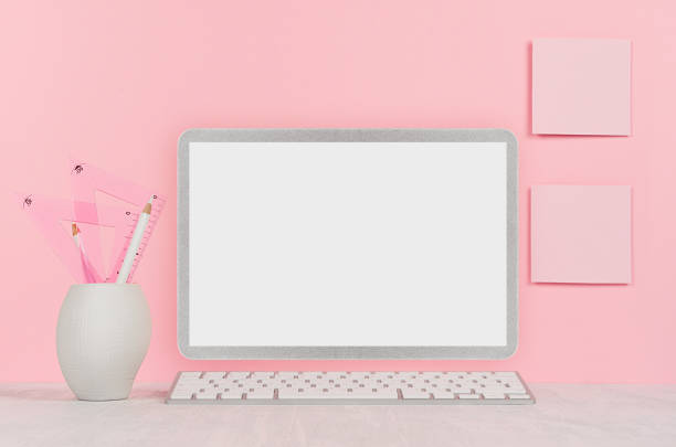 istock Fashion home interior with silver notebook computer with blank screen, books, stationery on soft pink background. 1050601168