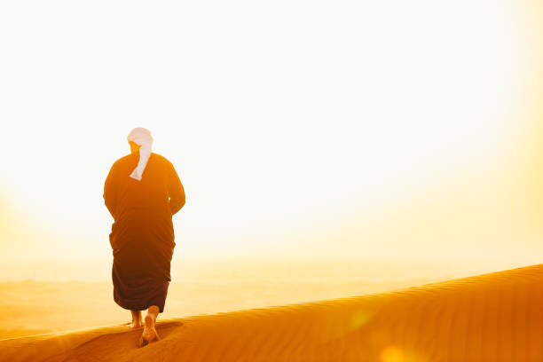 istock Arab walking on the sand dunes during morning sunshine 1050604320