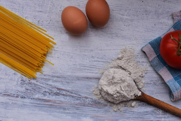 istock Raw homemade pasta with flour, eggs and tomato on rustic background. Uncooked spaghetti/ Kitchen- food background/ cooking concept 1050618736