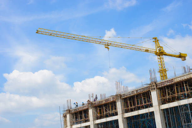 istock Crane and workers at construction site against blue sky 1050647022