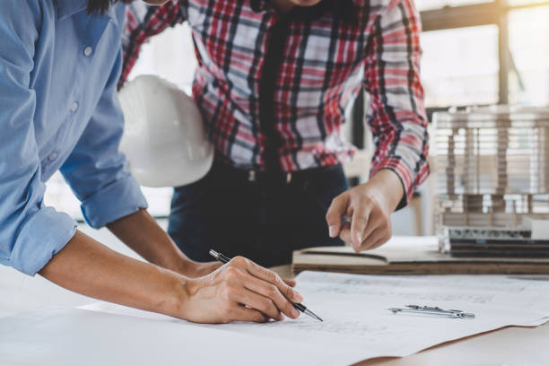 istock Construction concept of Engineer or architect meeting for project working with partner and engineering tools on model building and blueprint in working site 1050656810