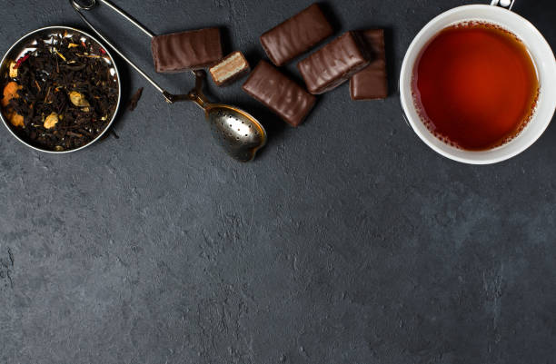 istock Chocolates and black tea with herbs. Metal tea strainer. Dark background. Copy space. Flat lay 1050663058