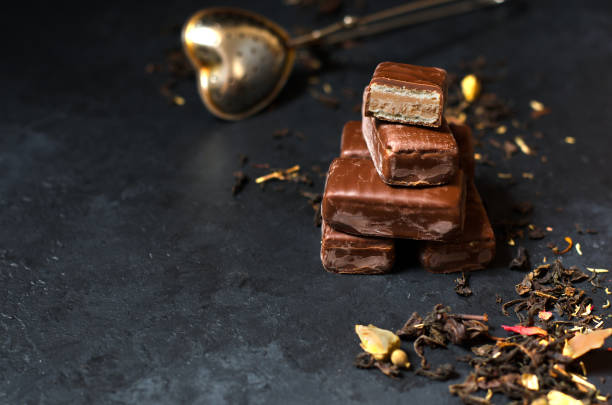 istock Chocolate candy and black tea with herbs. Metal tea strainer. Dark background. Copy space 1050663060