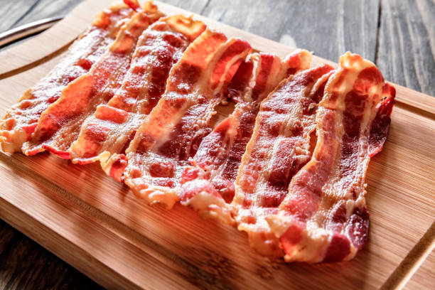 Roasted bacon on cutting board Roasted bacon on cutting board. Ingredient used in making Jam Bread or "Pan de Jamon" a Venezuelan Christmas food. Slice of Bacon stock pictures, royalty-free photos & images