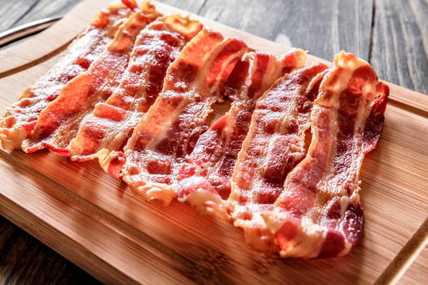 Roasted bacon on cutting board Roasted bacon on cutting board. Ingredient used in making Jam Bread or "Pan de Jamon" a Venezuelan Christmas food. cooked bacon slice stock pictures, royalty-free photos & images