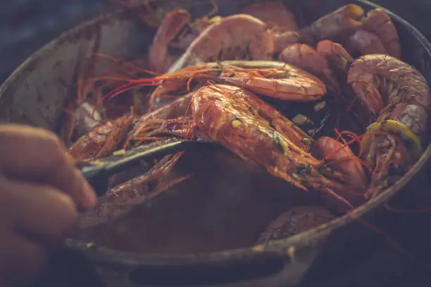 Photo of Tasty savory shrimps lie on a frying pan close-up. Toned image