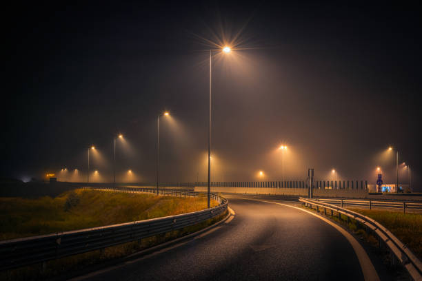 Highway exit during a foggy night with street lights and signs on the asphalt stock photo