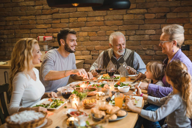 istock Happy extended family talking on Thanksgiving dinner at dining table. 1050696300