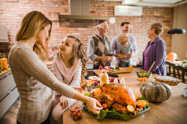 istock Happy mother and daughter communicating while preparing roasted turkey for Thanksgiving dinner. 1050705818