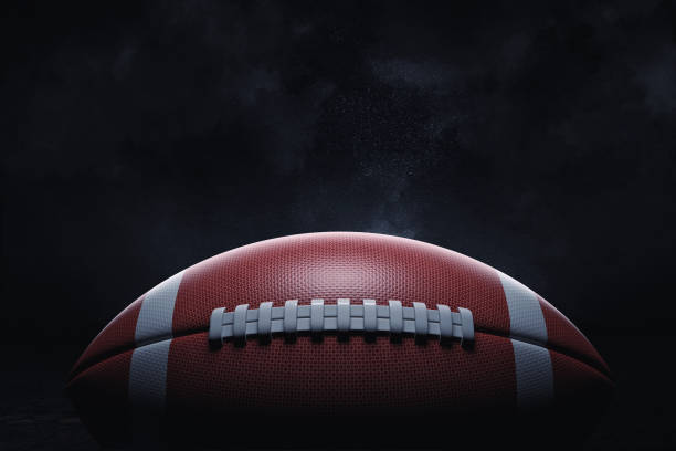 3d renderowanie skórzanej piłki do futbolu amerykańskiego leżącego ze szwami w skupieniu na ciemnym tle. - american football zdjęcia i obrazy z banku zdjęć