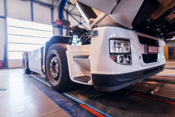 Photo of Side view of big truck in car workshop. Repairing old truck or making new in workshop.