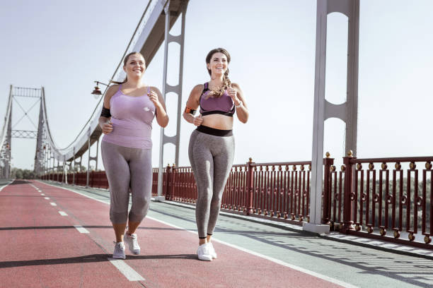 istock Nice positive women jogging together on the bridge 1050715860