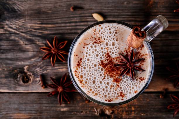 Homemade Chai Tea Latte with anise and cinnamon stick in glass mug. Top view Homemade Chai Tea Latte with anise and cinnamon stick in glass mug on wooden rustic background. Top view latte stock pictures, royalty-free photos & images