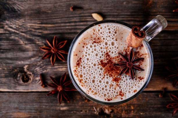 Homemade Chai Tea Latte with anise and cinnamon stick in glass mug. Top view Homemade Chai Tea Latte with anise and cinnamon stick in glass mug on wooden rustic background. Top view iced tea stock pictures, royalty-free photos & images