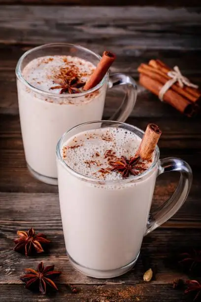 Homemade Chai Tea Latte with anise and cinnamon stick in glass mugs on wooden rustic background