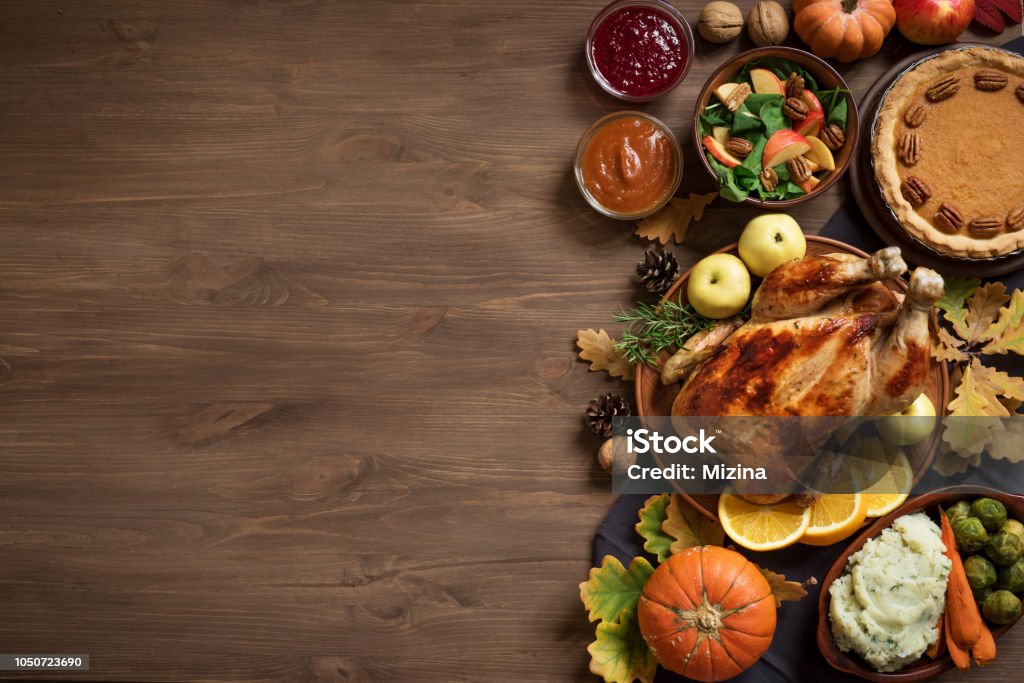 Thanksgiving Dinner background Thanksgiving dinner background with turkey and all sides dishes, pumpkin pie, fall leaves and seasonal autumnal decor on wooden background, top view, copy space. Thanksgiving - Holiday Stock Photo
