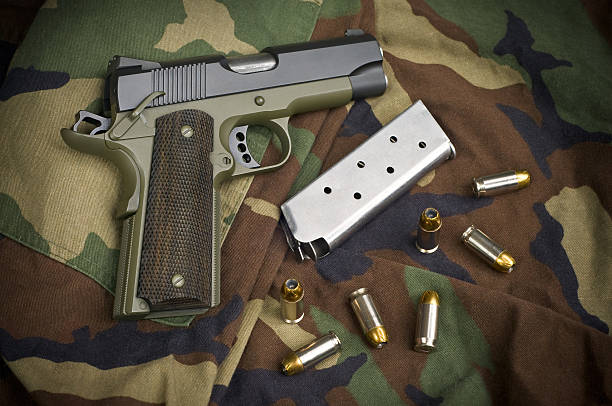 Firearm Pistol Clip And Hand Gun Ammunition on Camouflage .45 Firearm Pistol Clip And Hand Gun Ammunition on military camouflage background forty five caliber handgun stock pictures, royalty-free photos & images