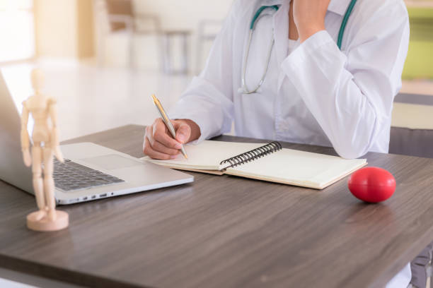istock Closeup portrait of female doctor is taking note something while looking at laptop computer 1050726588
