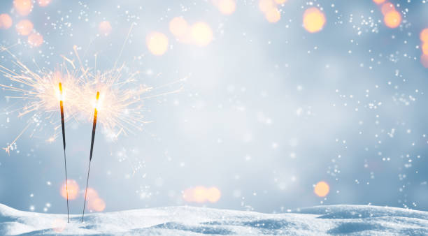 zwei brennende wunderkerzen im schnee - neujahr stock-fotos und bilder