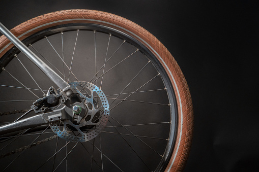 Bikes rear wheel with breaking disk, spokes, brown tire.