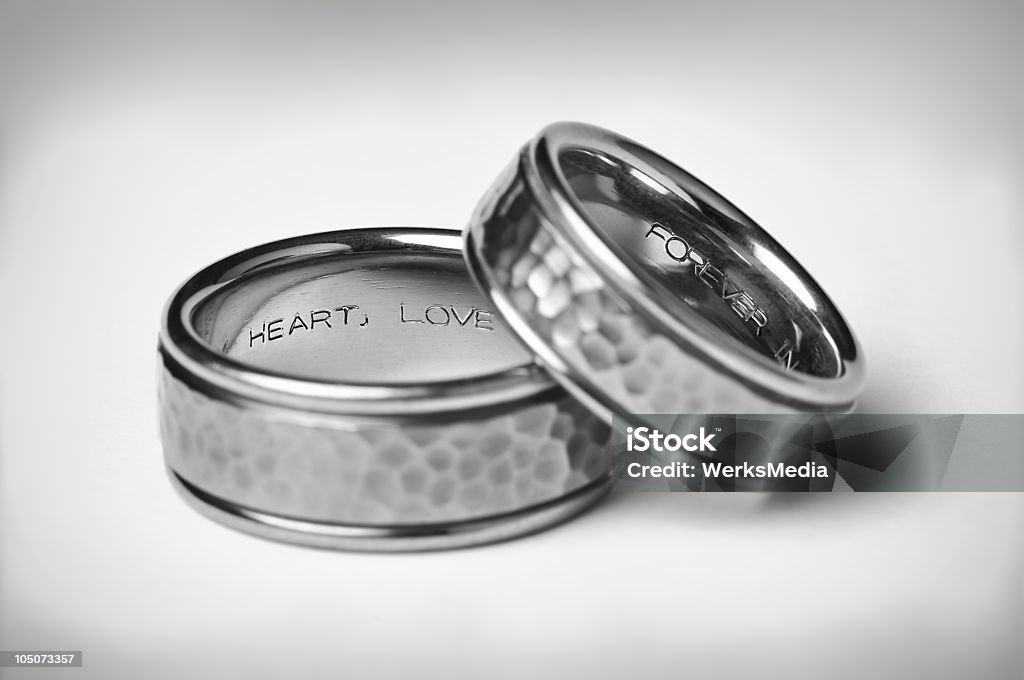 Two Titanium Silver Wedding Bands On White Two Titanium Silver Wedding Bands with heart, love, and forever inscriptions on a soft white gradient background with vignette symbolizing marriage. Engraved Image Stock Photo