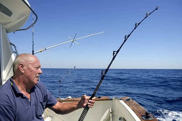 Angler senior big game sport fishing boat Angler elderly big game sport fishing boat blue summer sea sky big game fishing stock pictures, royalty-free photos & images