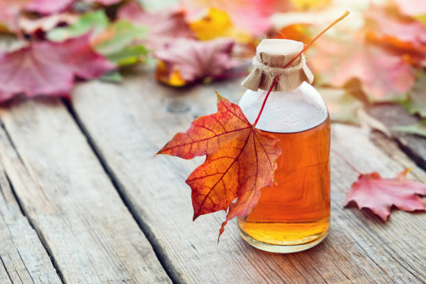 maple syrup or healthy tincture and fallen maple leaves. - maple tree imagens e fotografias de stock