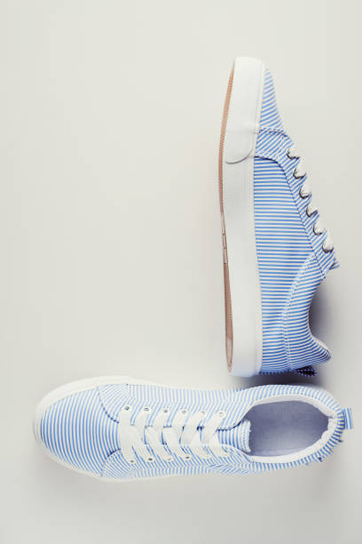 istock Blue striped female sneakers on a white background top view. Flat lay minimal background 1050746412