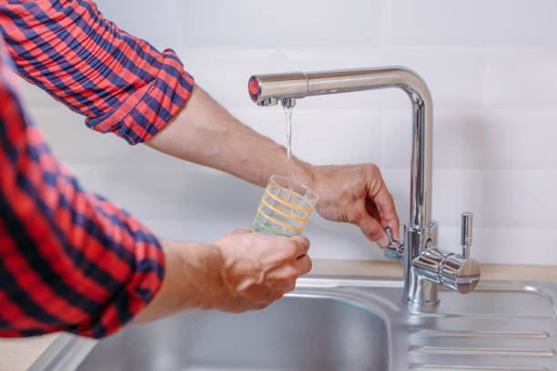 l’homme de verre verser de l’eau du robinet avec filtre propre dans la cuisine, gros plan - water filter photos et images de collection