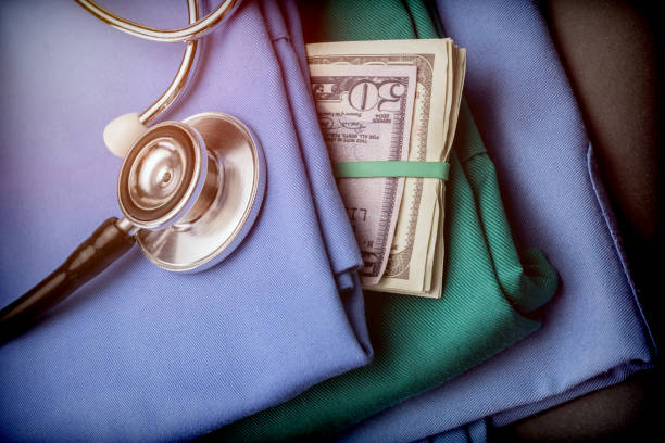 Wad pieniędzy dolara amerykańskiego w odzieży pielęgniarskiej, stetoskop na ubrania pielęgniarskie – zdjęcie