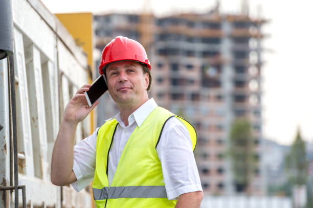 Satisfied construction site engineer speaking on his mobile phone. stock photo