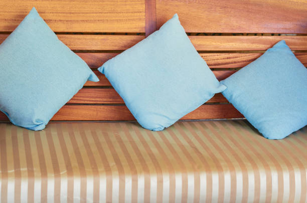 Blue cotton pillows lie on a wooden couch.