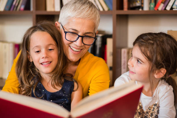 alte frau liest, enkelinnen - grandparent family reading inside of stock-fotos und bilder